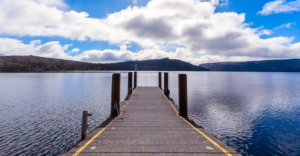 Jetty view on evening calm river on summer sky background.
