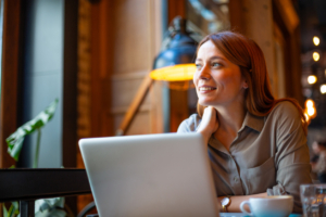 Woman working on laptop and looking away in cafe
