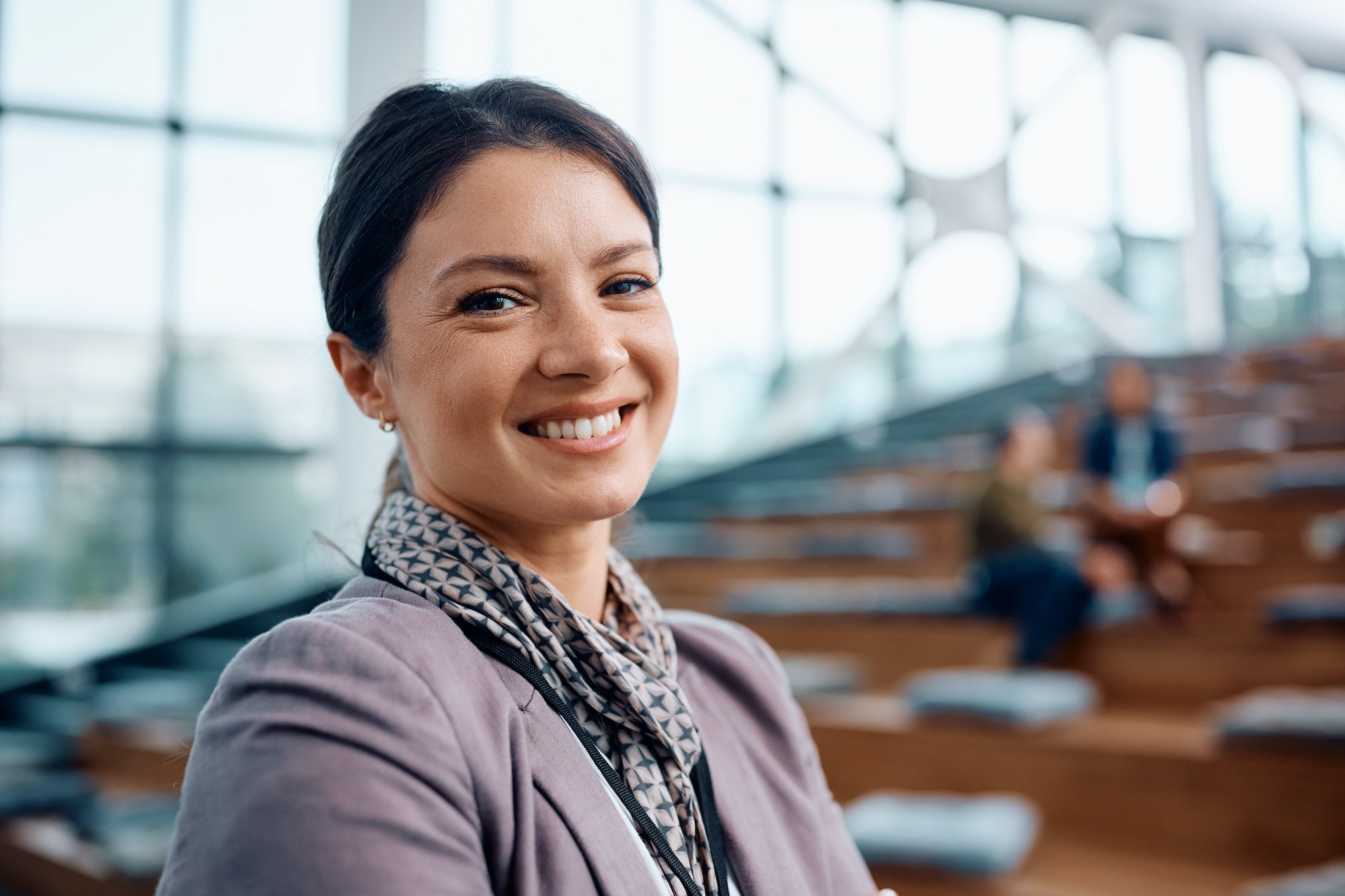 Happy female entrepreneur attending a business seminar in conference hall and looking at camera.